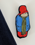 Close-up of an embroidered bear patch on a wool dress, featuring fine stitching and vibrant colors.