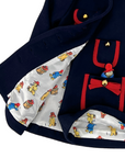 Close-up of the interior lining of a Little Goodall navy dress with red trim, featuring a playful patterned fabric and charming pocket details.