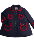 Girls dark blue wool winter coat with red trim, gold buttons, and satin print lining. A-line design with pockets and sleeve tabs.