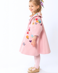 girl wearing a pink wool coat with floral and butterfly embroidery from the Rainbow Bloom , featuring a wide collar and elegant A-line silhouette