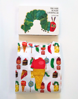 Folded Hungry Caterpillar romper for boys and girls with colorful food prints, made from 100% cotton, displayed with the matching board book