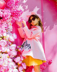 Fashionable child in a pink wool coat with zebra appliqué, standing near a pink floral backdrop