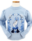 Light blue sweater with puffed shoulders and ribbed edges, featuring a dog on a blue tasseled cushion framed by floral patterns