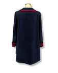 Back view of a womens deep blue wool coat with red trim and a tailored A-line silhouette.