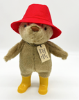 Paddington Bear 10" plush toy with red hat, yellow boots, and "Please Look After This Bear" tag, perfect for collectors and kids ages 3+