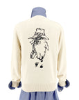 Back view of the Adult Paddington Bear Sweater in ivory cotton knit, featuring Peggy Fortnum’s illustration of Paddington Bear walking away