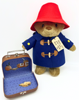 Paddington Bear plush wearing a blue duffle coat and red hat, with a small suitcase