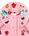 Close-up of pink wool girls' coat featuring embroidered flowers, butterfly appliqués, and floral lining for a charming, whimsical touch