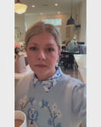 Lady showcasing her Willa Heart blue dog sweater styled with a classic printed Willa Heart shirt for a polished and preppy layered look