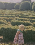 video showcasing A young girl walking gracefully in a strawberry-print dress with a green leaf colla
