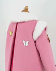 Close-up of pink wool girls' coat with a rainbow, gold and silver butterflies, and a soft faux fur collar