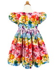 Back view of the Rainbow Bloom Dress on form, showcasing its vibrant floral and butterfly print, puff sleeves, and delicate tie waist
