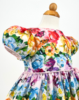 Close-up of Rainbow Bloom Party Dress featuring puff sleeves, pastel floral print, & delicate butterfly details, highlighting fabric texture and design