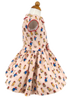 Side view of a vintage-inspired girls' dress with red trim, cap sleeves, belted waist, and full skirt, made from soft printed cotton.