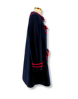 Side view of a women's deep blue wool winter coat with red trim and gold buttons.