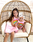 Sisters wearing matching rainbow dress and romper in Sunset Pink with colorful appliques and cloud peplums