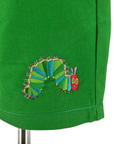 Close-up of embroidered Very Hungry Caterpillar on green cotton toddler and kids' shorts, showing colorful stitching detail.