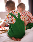Back view of a toddler wearing a green Hungry Caterpillar romper with crossed straps and a food print shirt