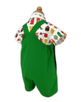 Back view of Very Hungry Caterpillar romper displayed on form, showing green twill fabric, crisscross straps, and colorful food print shirt