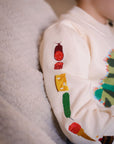 Close-up of a child wearing the Very Hungry Caterpillar sweater, showing detailed embroidery of food from the story on the sleeve