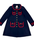 Charming women's deep blue wool winter coat with gold buttons and red trim.