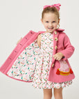 Model wearing pink dog coat, exposing the pink dog satin lining.