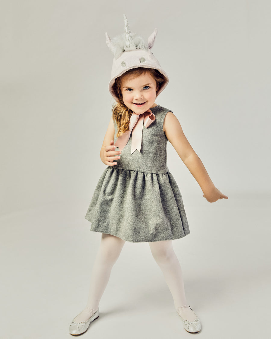 Front view of girl modeling a Unicorn hat tied as a bow underneath her chin.