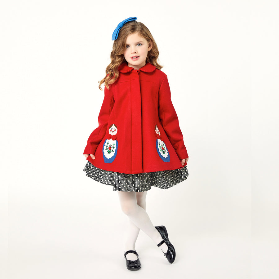 Girl modeling red coat while curtsying.