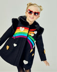 Model showing front of black coat, dissplaying the full rainbow with silver and gold hearts.