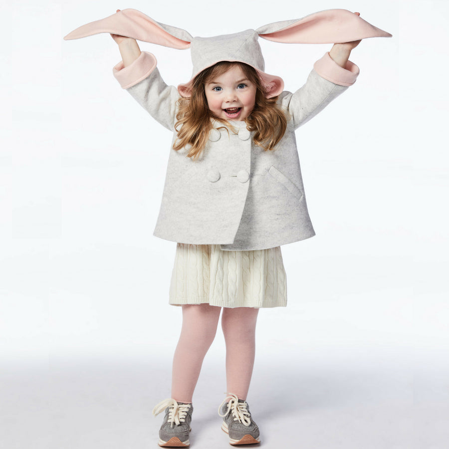 girl modeling grey bunny coat, holding up grey and pink bunny ears.