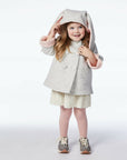 girl modeling grey bunny coat, holding up hood.