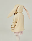 Back view of the tan bunny coat on the model, displaying floppy bunny ears with the hood up.