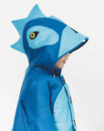 Side view of a young boy wearing the Blithe Blue Dinosaur Coat, featuring a playful dinosaur hood with spikes and a button-up front