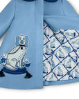 Close-up of girls' blue wool coat featuring embroidered dog motif with tassels and satin lattice print lining with dog illustrations.