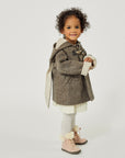 Toddler girl in little Goodall brown wool bunny coat with floppy ears, toggle closures, and a hood, standing in profile