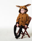 Child sitting in a Little Goodall Frolicsome Fawn Coat, featuring a playful hood with large ears and front pockets