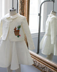 Ivory linen bunny jacket and dress set by Little Goodall displayed on a mannequin, reflected in an ornate mirror