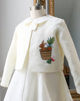 Ivory linen bunny jacket by Little Goodall on dress form, featuring embroidered bunny in a bushel of carrots and radishes