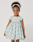Girl wearing the Carrot and Dot Dress in mint with a bamboo trellis print, cap sleeves, and a gathered balloon skirt,with her hands at sides