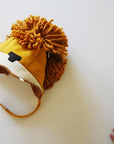 A handmade wool-blend felt lion hat with earflaps and a velcro chin strap, perfect for toddlers in cold weather.