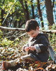 Child wearing Little Goodall Flopsy Bunny coat in a forest, featuring soft wool, plush lining, toggle closures, and bunny ear hood for warmth