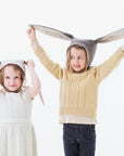 Two children wearing wool felt Flopsy Bunny Hats with soft fleece lining and long floppy ears for dress-up and warmth.