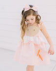 Girl wearing Little Goodall Pink Gingham Bunny Love Dress with matching hair bow, bunny face bodice, and dangling carrot details.