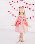 Girls in Little Goodall pink flamingo dress with sleeveless design and layered peplum, perfect for summer parties