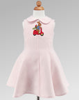 Blush Linen Scooter Bunny Dress on form, featuring embroidered bunny on red scooter, sleeveless design, and flared skirt for toddlers and girls.