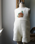 Ivory linen bunny romper with embroidered basket, displayed on a dress form. Classic gender-neutral baby outfit by Little Goodall