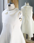 Close-up of ivory linen dress on a mannequin, showing Peter Pan collar, princess seams, and back button details