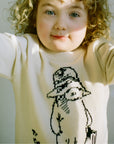 Close-up of child wearing the Sweater in ivory, showcasing the black knit illustration of Paddington Bear by Peggy Fortnum on soft cotton