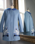 Ladies Aldrich and Madame De Bleu Coat in soft merino wool, featuring embroidered blue Staffordshire dog motifs with tassel details, reflected in a mirror