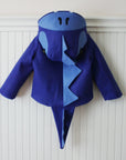 Back view of the Blithe Blue Dinosaur Coat by Little Goodall, featuring a ridged dinosaur hood, plush tail, and cozy wool blend fabric